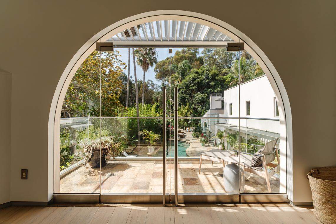 The spacious primary bedroom features custom closets and tranquil views of the pool and gardens, delivering a peaceful, resort-like retreat just minutes from the beach.