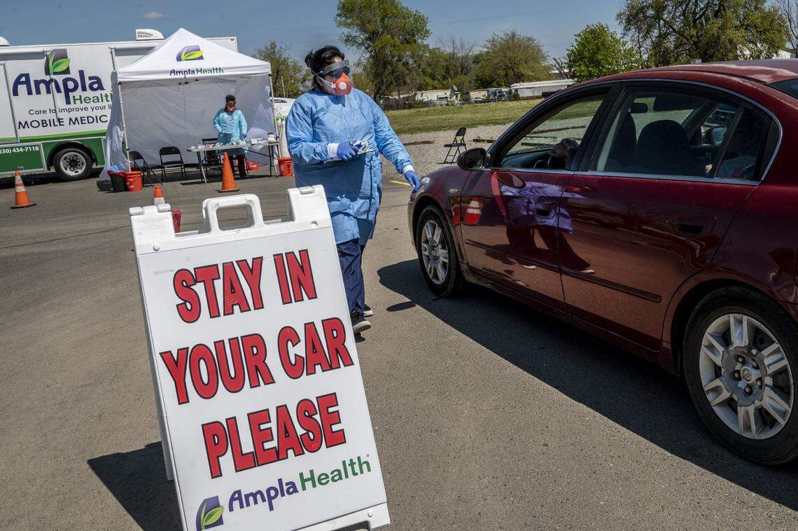 Signs direct drive-through patients to stay in their cars on Friday, March 27, in Yuba City as they are screened by Ampla Health workers with with a series of questions after having have their temperature taken. “Everyone will be screened but not everyone will be tested,” said Rocio Valdez, director of communications on site.