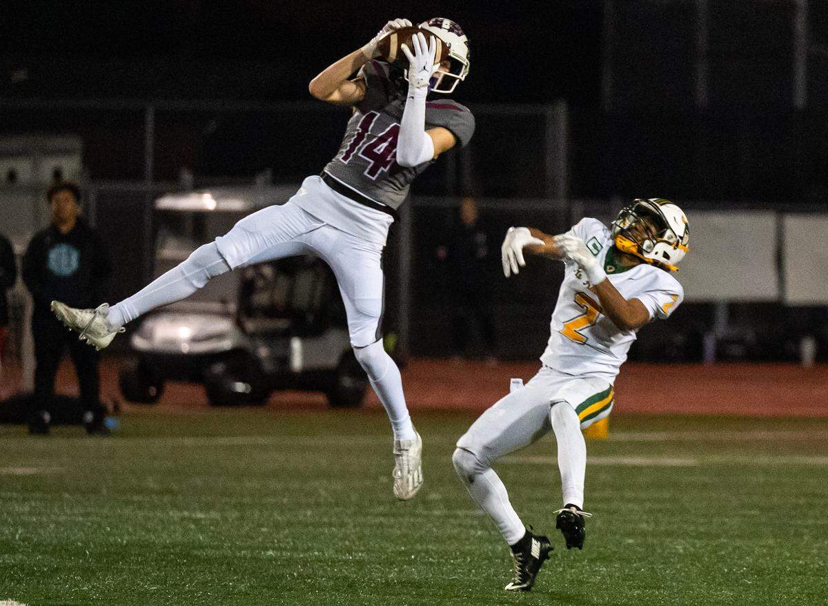 Woodcreek Timberwolves cornerback Ethan Keim (14) out jumps the Rio Americano Raiders’ Arnez Campbell (2) for an interception in the second quarter of they CIF Sac-Joaquin Division III semifinal playoff game in Roseville on Friday.