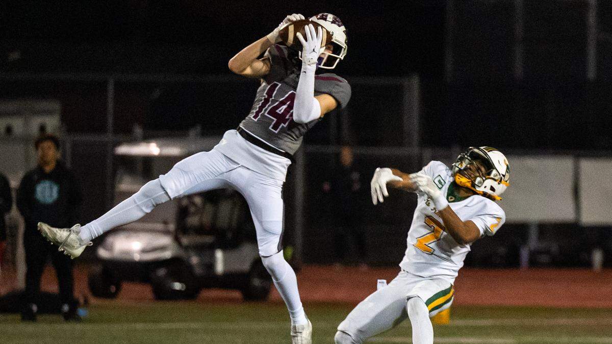 Woodcreek Timberwolves cornerback Ethan Keim (14) out jumps the Rio Americano Raiders’ Arnez Campbell (2) for an interception in the second quarter of a CIF Sac-Joaquin Division III semifinal playoff game in Roseville on Friday, Nov. 21, 2025. 