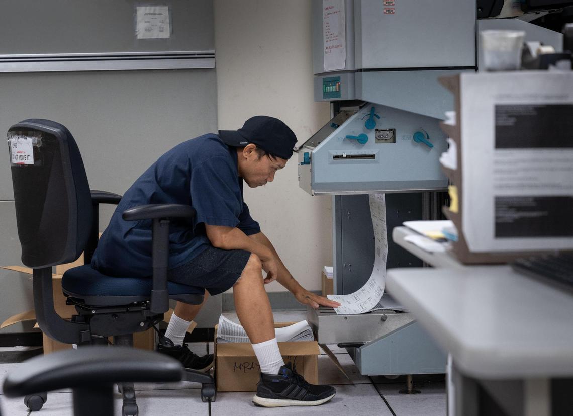 IT technician Erwin Corspuz prepares printed pay paychecks for California state workers at the state controller’s printing facility on Aug. 24, 2023. 