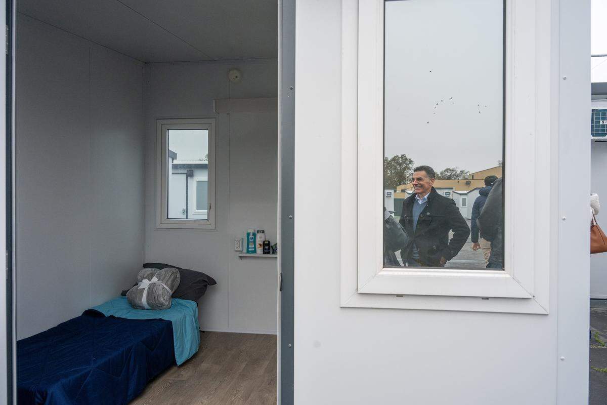 Sacramento Department of Community Response Director Brian Pedro is reflected in the window of a tiny home, which will be operated by The Gathering Inn, during a news conference announcing 135 additional tiny homes on the city's two campuses on Roseville Road on Thursday.