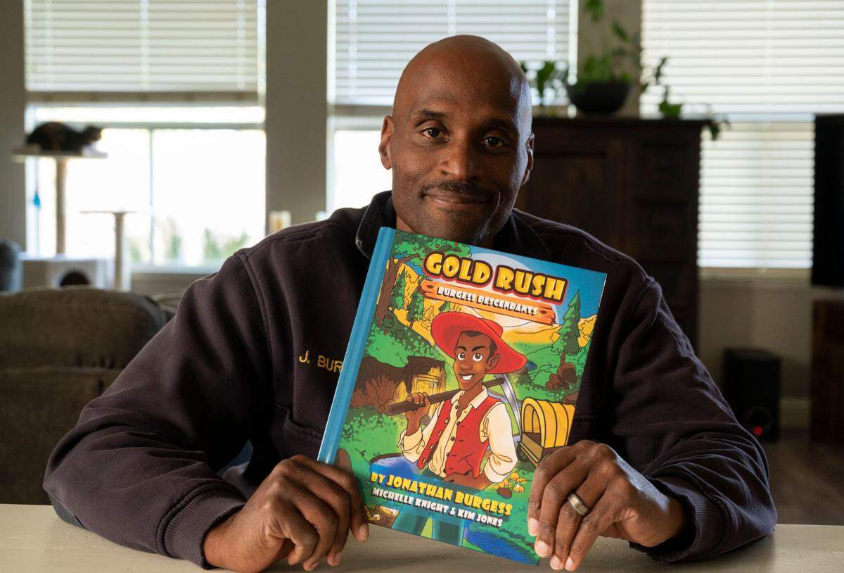 Jonathan Burgess holds his children’s book “Gold Rush: Burgess Descendants” on Wednesday, March 16, 2022, in Sacramento County. Burgess, a Sacramento Fire Department battalion chief and advocate for reparations for Black Californians, died May 11 at age 52 after a four-year battle with ALS.