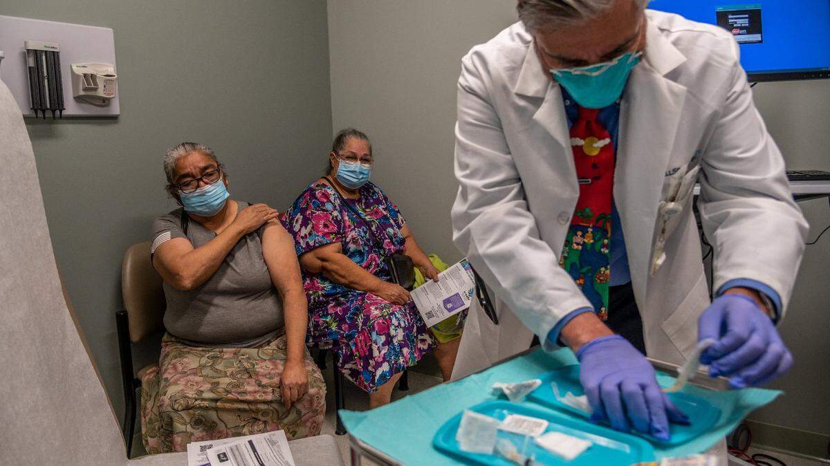 Francisca Virelas, 66, left, holds her sleeve after getting the COVID-19 vaccine as her friend Virginia Covarrubias, 69, waits for shot from Dr. Francisco Aguirre at the WellSpace Health South Valley Community Health Center in Sacramento on Wednesday, Feb. 10, 2021. “I thank God that we survived last September when we had the coronavirus – when a lot of people were dying. Being that we are seniors the chances were very slim, but we pulled through,” Covarrubias said.