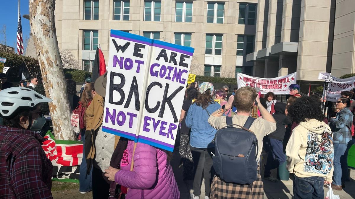 A demonstrator holds a sign outside the Robert T. Matsui Federal Courthouse on Saturday as protesters rally against the incoming Donald Trump administration in downtown Sacramento.