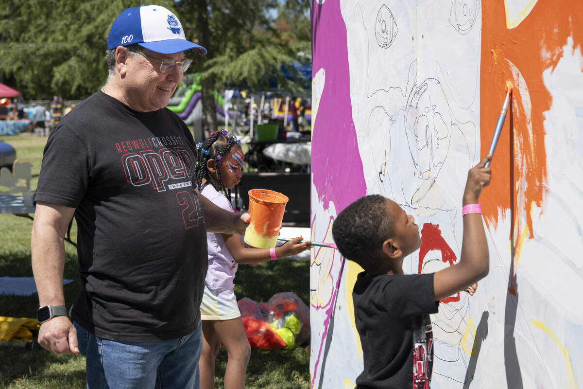 Scott Koppel, left, Millie Lane, center, and Micah Lane work on a community mural during the Sacramento Banana Festival at William Land Park on Sunday.