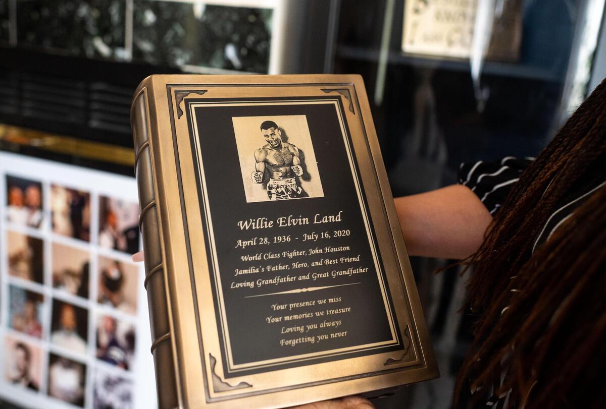 Jamilia Land holds an urn adorned with an image of her father from his days as a professional boxer while on April 1.