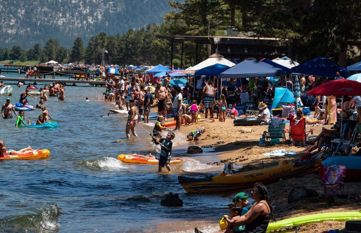 People flock to the shores of Lake Tahoe at Camp Richardson near South Lake Tahoe on a hot Saturday in July 2020.