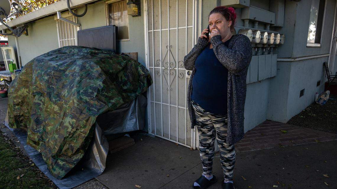 Kristi Phillips, 49, on the verge of eviction, talks on a cellphone on Monday next to a pile of her belongings covered by a tarp outside the Sacramento apartment complex where she had been staying with her son Ty, 14. She was juggling calls with her son’s high school principal about Ty’s recent truancy and the homeless outreach programs she contacted on Friday.