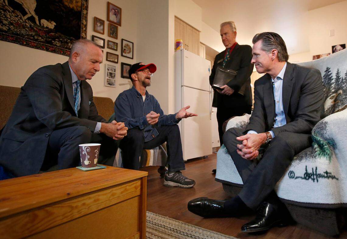 Gov. Gavin Newsom, right, visits veteran Vern Davis, second from left, during his tour of the Mather Veterans Village in Rancho Cordova in 2019. Newsom, accompanied by Sacramento Mayor Darrell Steinberg, left, and Rancho Cordova Mayor Robert McGarvey, standing, toured the facility that provides low cost housing for veterans. Davis, who at had times has been homeless, told Newsom about his difficulties finding affordable housing before moving into the veterans village that provides low cost permanent housing for veterans.