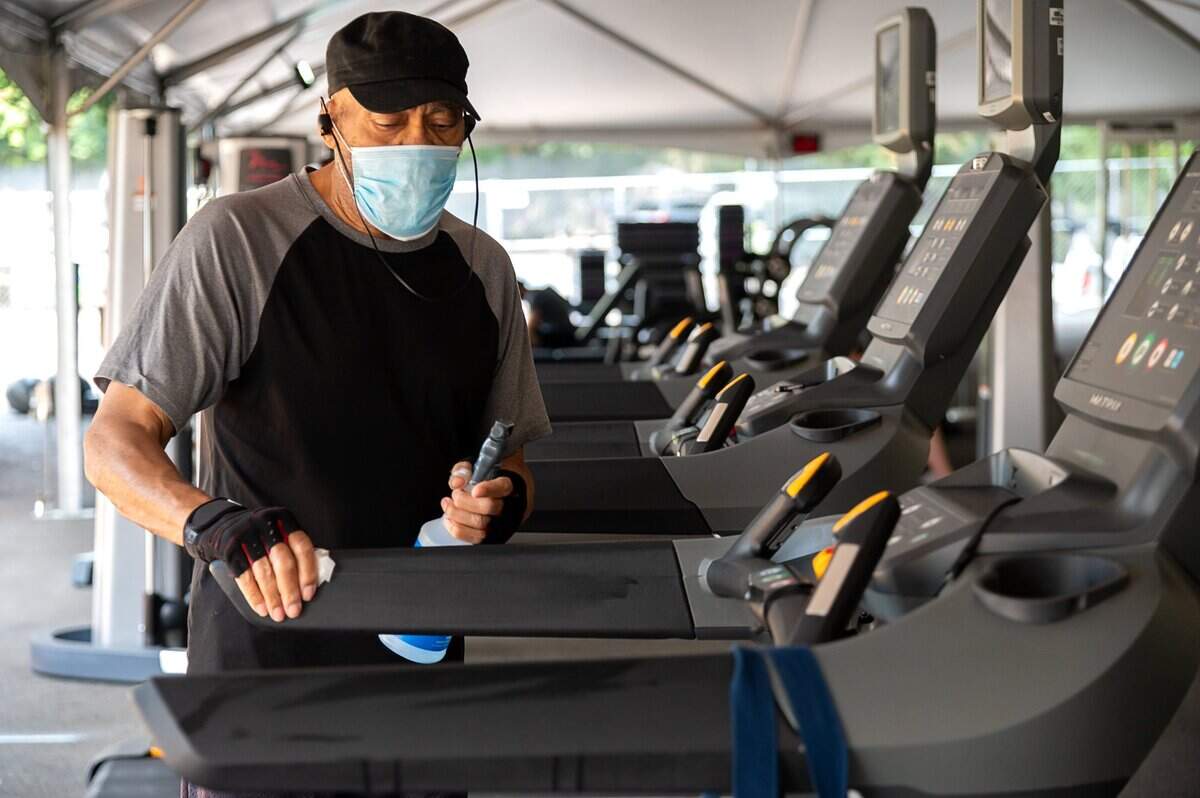Harvey Banes, 81, disinfects equipment after his work out at the outdoor workout area set up in the parking lot at the California Family Fitness in the Greenhaven area on Friday, Sep 4, 2020.