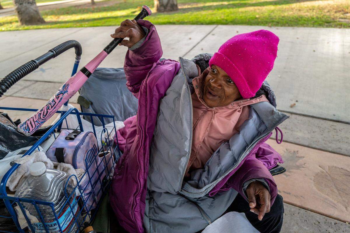 Sharon Pendarvis uses a T-ball baseball bat to protect herself while sleeping outside in a folding chair in McClatchy Park in the Oak Park neighborhood in November. “I will never live in a transitional living house again because of what I went through,” she said.