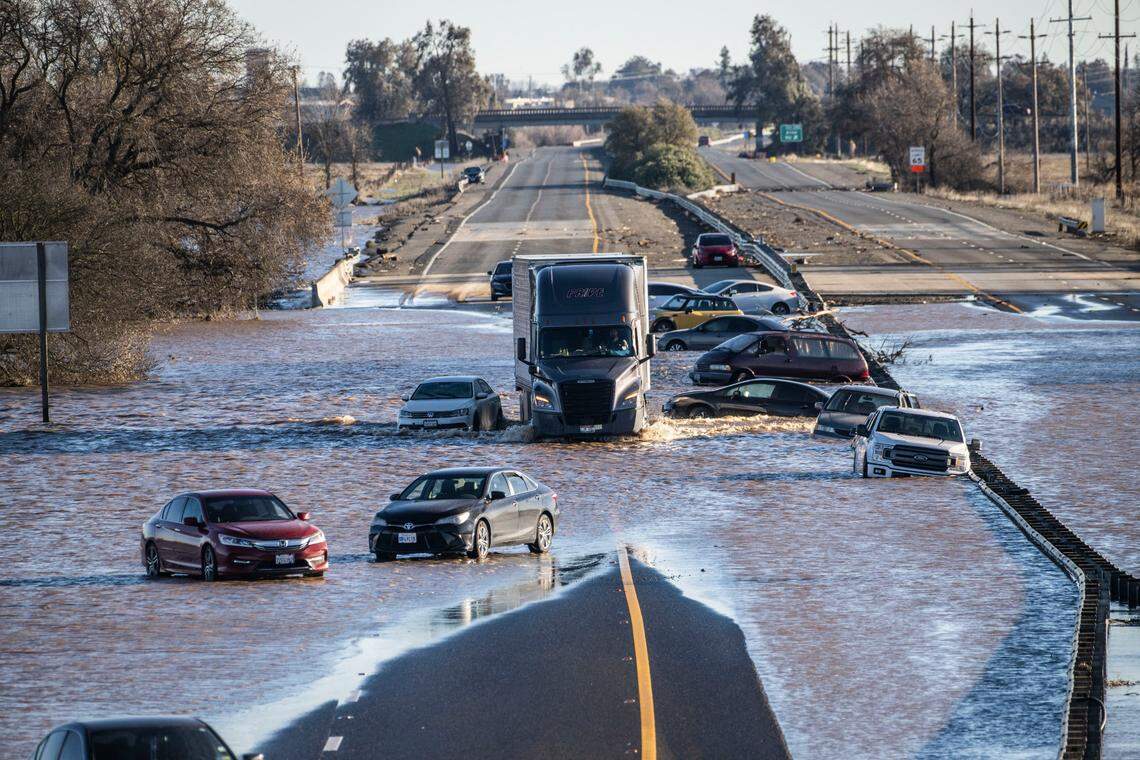 A semi truck drives on Highway 99 on Sunday afternoon, past abandoned cars that were stranded amid flooding near the Dillard Road exit in south Sacramento County.