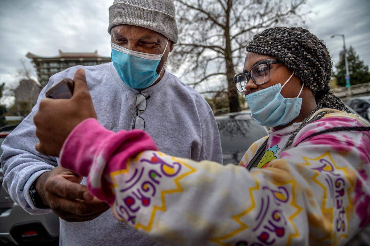 Quinton Watts gets a lesson on a mobile phone from daughter Daisha Watts, 19, outside the Sacramento Valley Station where several advocates came to greet him on Wednesday, Feb. 3, 2021. Afterward he talked about hugging a tree. “Man, fresh air!” he said.
