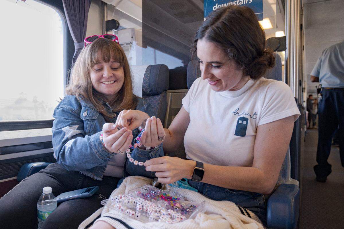 Hillari Bynum, left, and Annmargaret Dwyer, right, are creating friendship bracelets for Taylor Swift’s concert on Friday, July 28, 2023, during the three-hour train trip from Sacramento to Levi’s Stadium.