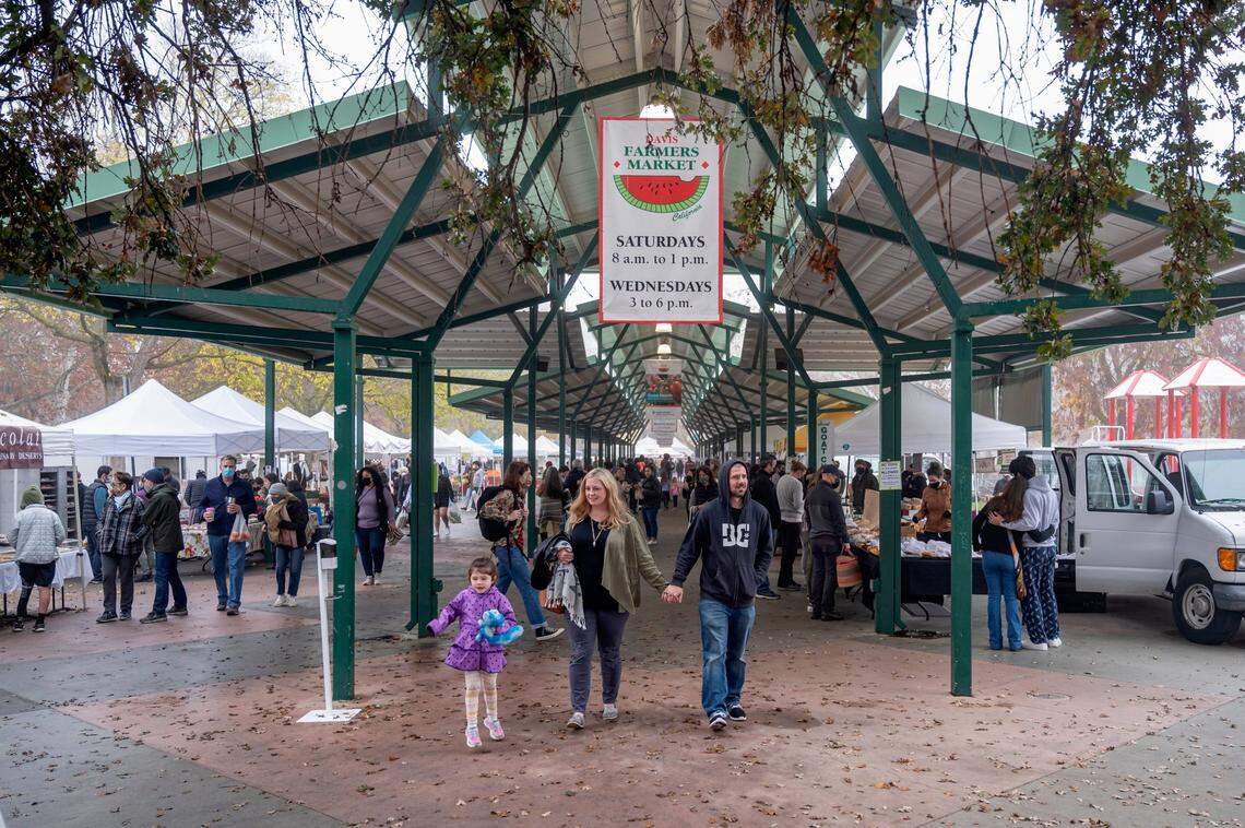 Kristen Patchett, center, of Sacramento, walks with Tim Thixton and his daughter Grace, 5, at the Davis Farmers Market at Central Park in Davis on Saturday, Dec. 4, 2021.
