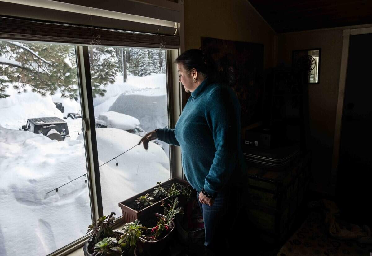 Erin Kelly points to the buried grill in the snow on Monday, March 6, 2023, in South Lake Tahoe. “It’s been a lot and we’re supposed to have a warm storm coming in. So that’s pretty bad,” said Kelly.