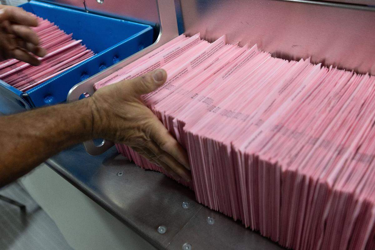 An office worker at the Sacramento County Voter Registration and Elections office places ballots on a machine before signature verification on Tuesday, Nov. 5, 2024.