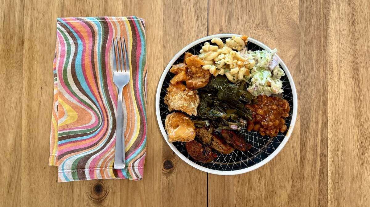 Vegan versions of hot links and fried chicken from Bay Area-based food truck Vegan Mob are served alongside candied sweet potatoes, greens, slaw, beans and “Smackaroni” on Sunday, April 12, 2026 in Sacramento.