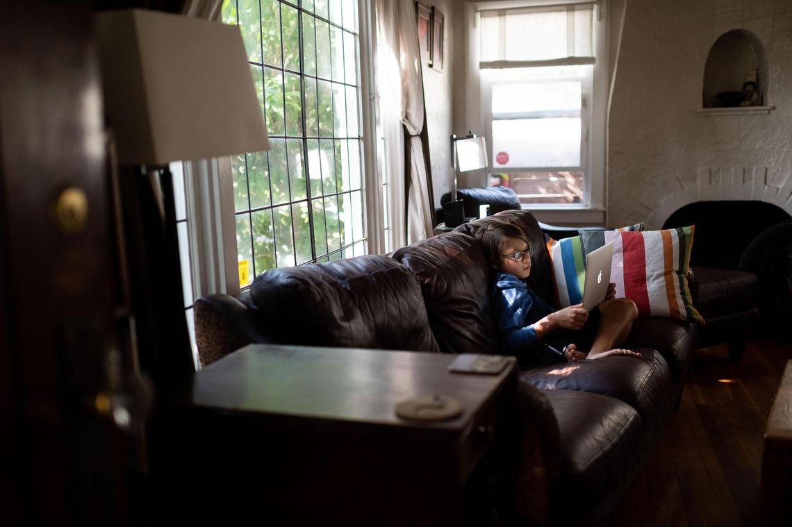 Enzo Martinez-Vaughan, 10, sits with his laptop on a couch in his living room, where he does much of his schoolwork, on Tuesday, May 12, 2020, in Sacramento. His parents, Marco Martinez and Betsy Vaughan, have also been working at home, mainly in a shared office and their bedroom, depending on the level of privacy needed for various video calls.