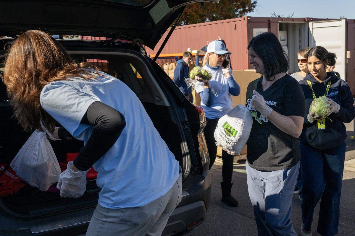 Sacramento City Councilmember Lisa Kaplan, center, helps distribute food with other volunteers at Joey’s Food Locker, a program run by the Natomas Unified School District, on Friday in Sacramento. The program is set to distribute Thanksgiving meals to more than 1,000 families.