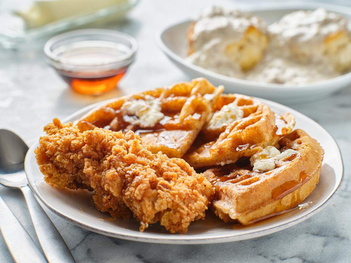 Stock image of fried chicken and waffles breakfast with maple syrup.