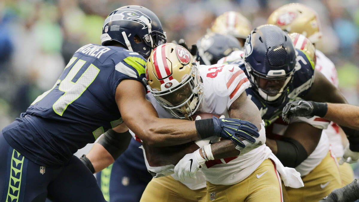 Jeff Wilson Jr., center, is tackled by Seattle Seahawks defenders Dec. 2 in Seattle. Taking over for an injured Matt Breida, Wilson amassed a team-high 134 all-purpose yards in the loss and will start Sunday against the Denver Broncos.