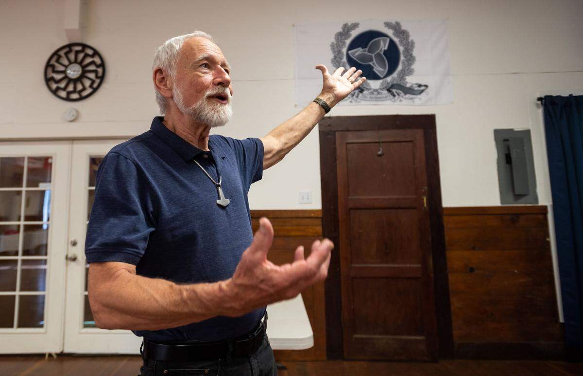Stephen McNallen, founder of the pagan whites-only Asatru Folk Assembly, talks about the symbolism of the interlocked drinking horns behind him in the ASA’s “Odinshof” on July 27, 2021, in Brownsville, Yuba County. “Those three interlocked horns represent the wisdom and the inspiration of Odin,” McNallen said. “To me, that symbolizes our future … a future of inspiration and outreach, and forward expansion.”