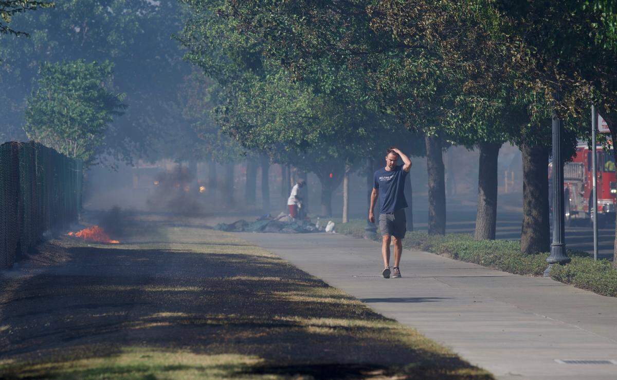 Robert Brown, who lives near where a grass fire broke out along 7th Street between Railyards Boulevard and North B Street on Friday, walks back after offering assistance.