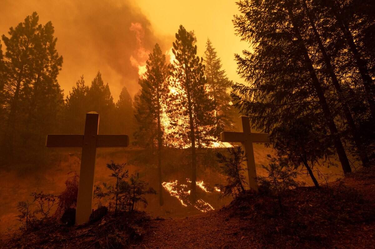 25. The Caldor Fire burns behind two crosses from a roadside memorial on Morman Emigrant Road on Tuesday, Aug. 17, 2021 near Sly Park.