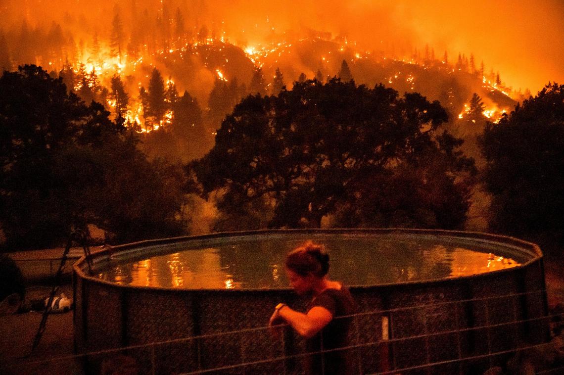 Angela Crawford leans against a fence as the McKinney Fire burns a hillside above her home outside Klamath National Forest on Saturday.