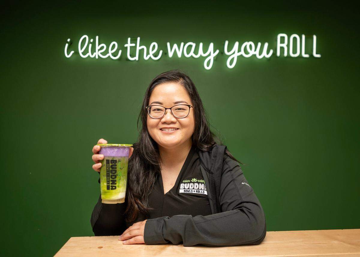 Eileen Le, marketing manager at Buddha Bowl & Rolls, holds a Ube-Bae matcha latte at the midtown restaurant earlier this month.