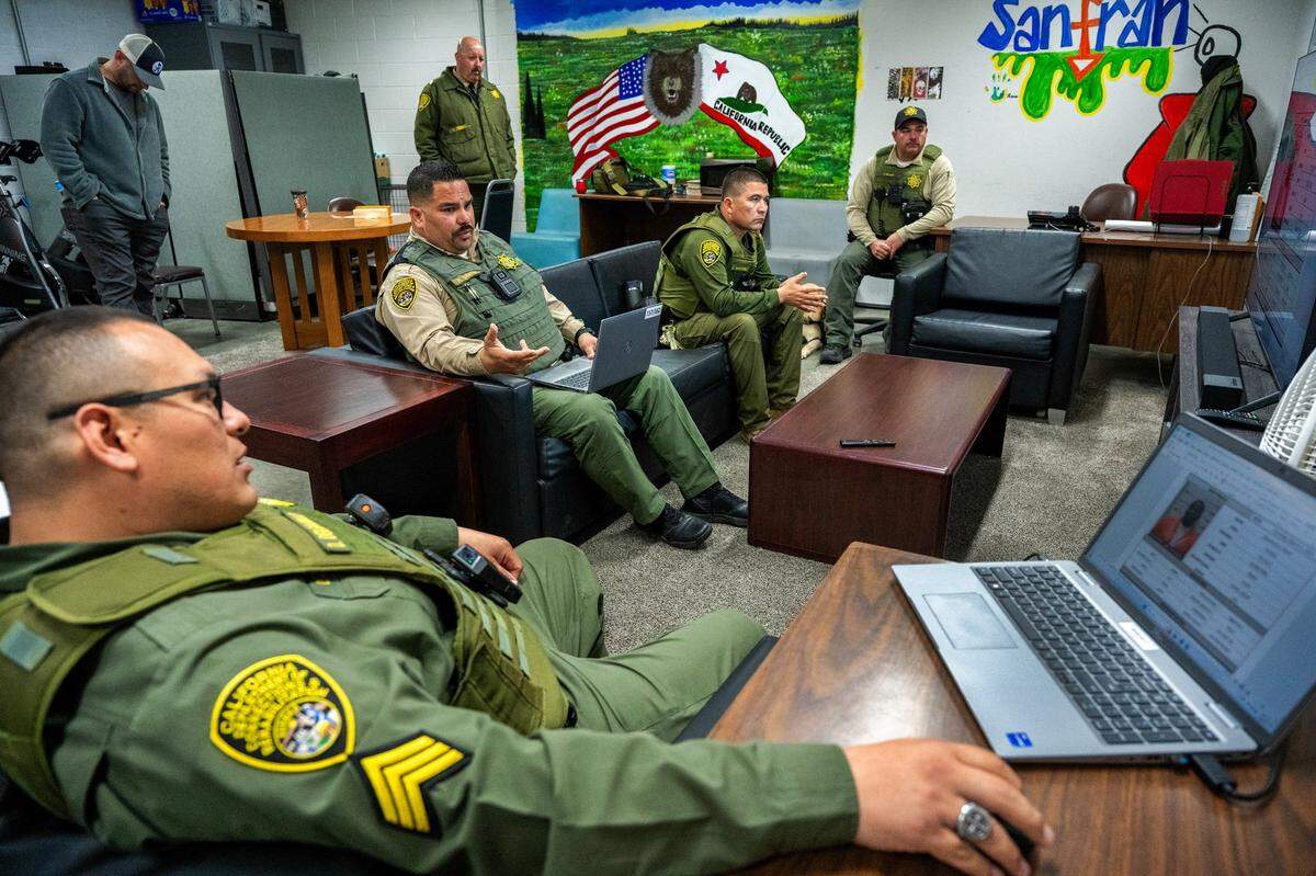 Correctional Officer Ricardo Garcia, center left, discusses with the background of an inmate – who would soon enter the room to participate in a therapy program – with other members of the Salinas Valley Resource Team at the high-risk prison in March. The team started with two members and now has grown to 12 members.