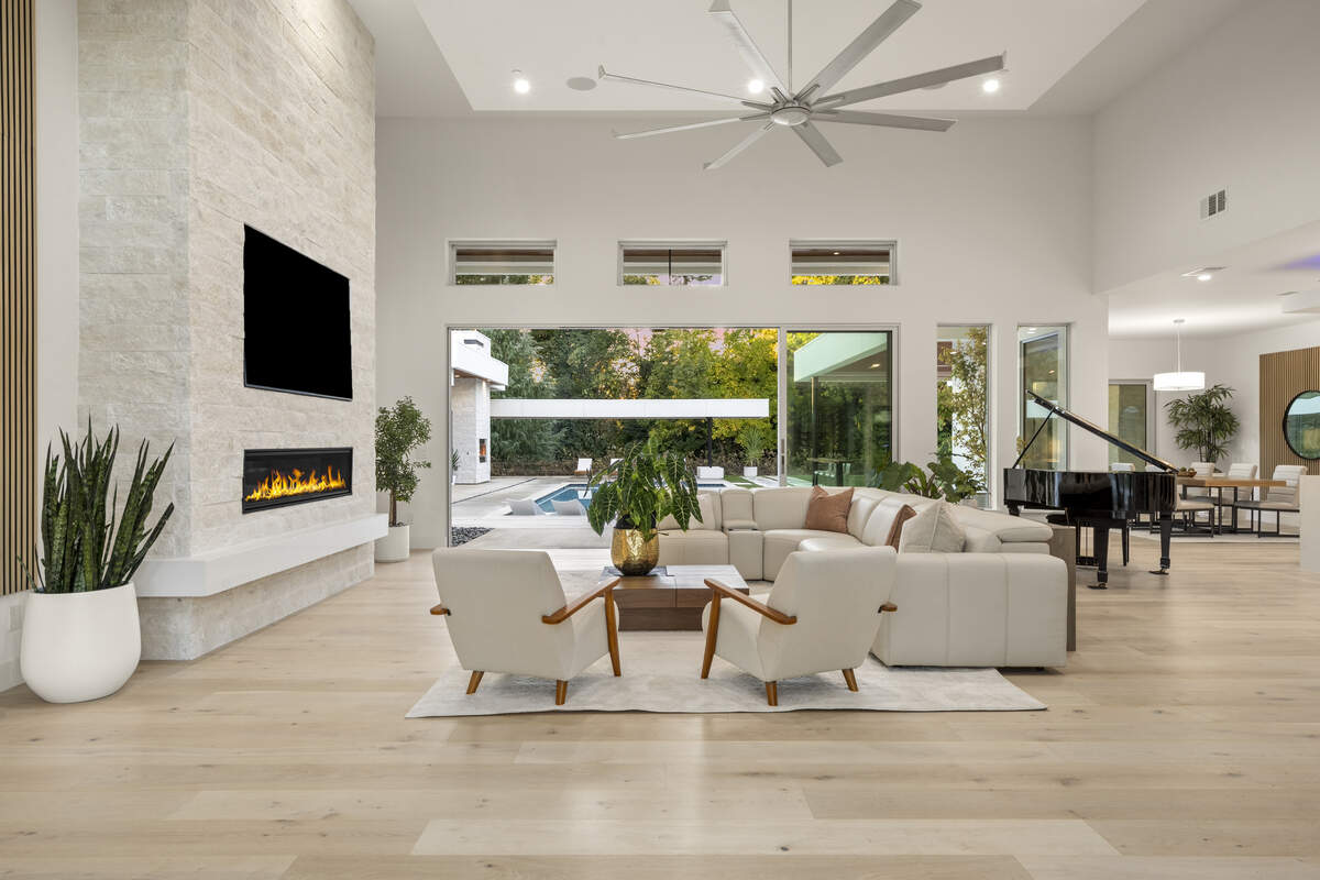 Soaring ceilings, a statement-size fan and a floor-to-ceiling stone fireplace wall define the main living room’s dramatic scale.