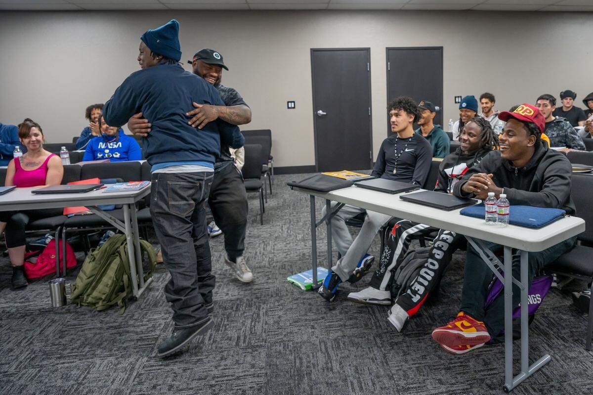 Sidney Randle hugs a student in a class at the People Working Together training facility in Sacramento on Tuesday, March 25, 2025. Randle, who learned job skills at PWT after serving 10 years in prision, helps mentor people in the program. Now a journeyman, Randle said he aspires to get a contractors license and run his own business.