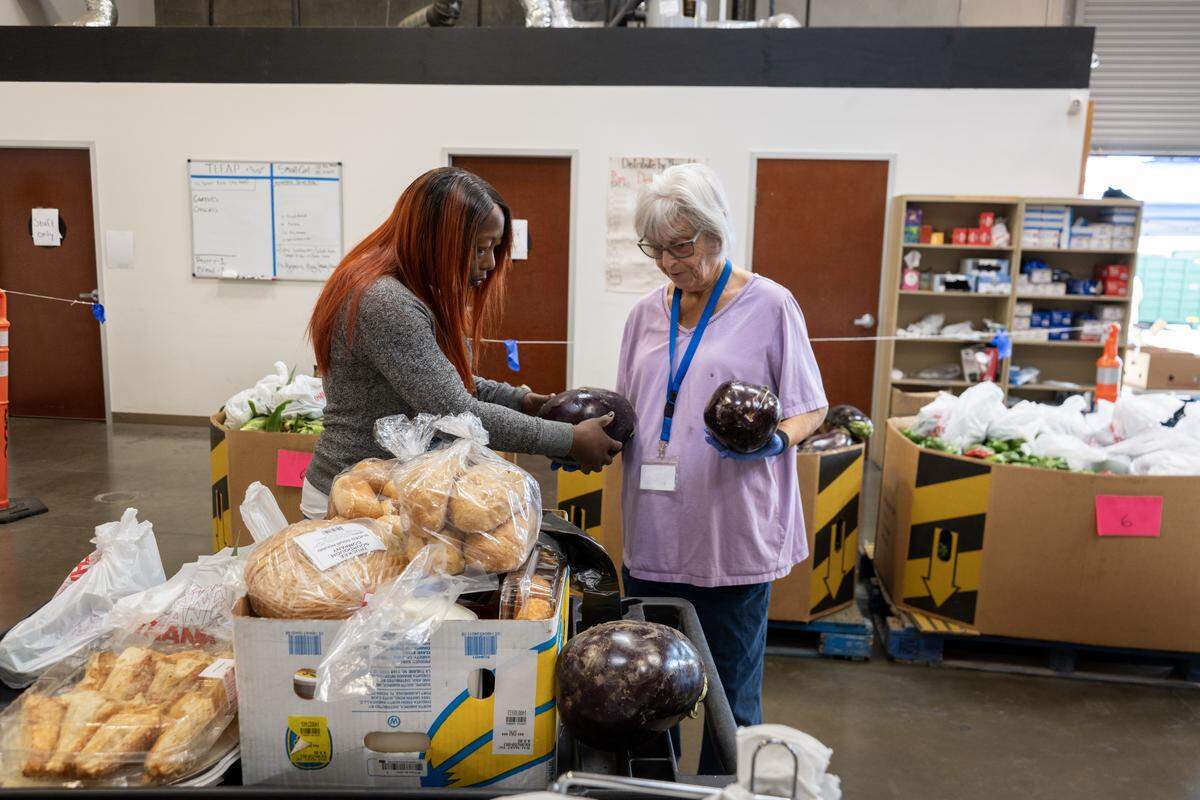 Samora Simpson receives assistance from Linda Montgomery, an Elk Grove Food Bank volunteer, on Saturday in Elk Grove. The food bank has seen a significant increase in clients seeking help due to the pause in the SNAP program and the ongoing government shutdown.