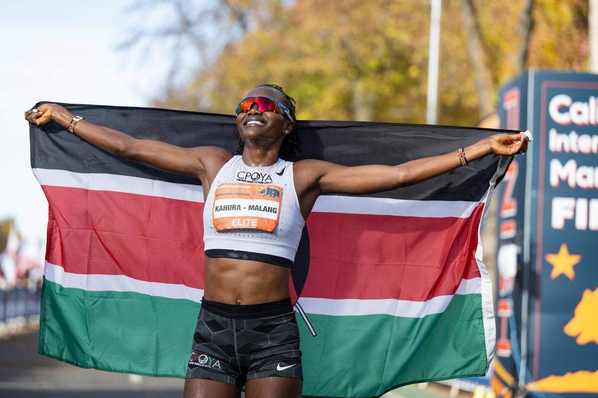 Grace Kahura, of Longmont, Colo., smiles as she holds the Kenyan flag at the finish line after winning the 40th California International Marathon from Folsom to the state Capitol in downtown Sacramento, on Sunday, Dec. 3, 2023.