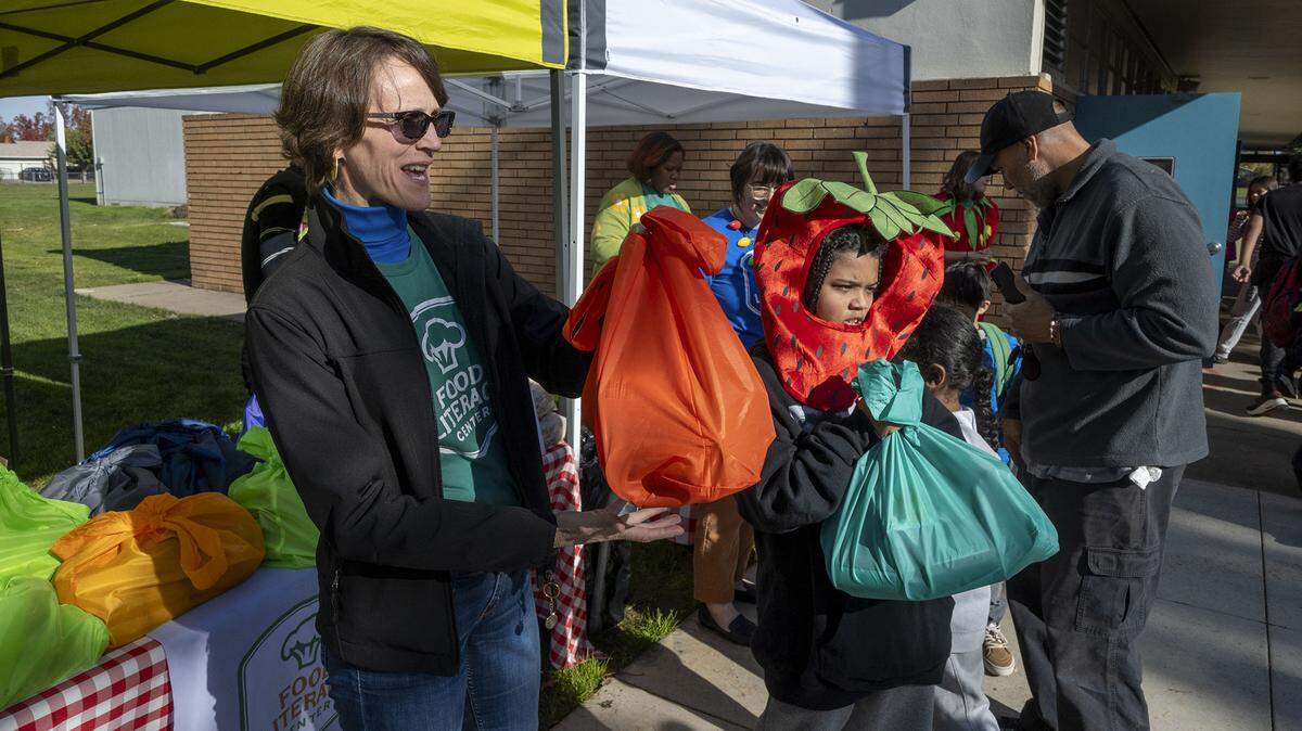 Amber Stott, left, founder of the Food Literacy Center, stands with volunteer Donovan Hall-Ramsey, 9, to hand out 50 food kits and recipes at John Sloat Elementary School on Dec. 1 for kids to take home and cook. The Food Literacy Center Kitchen is asking Book of Dreams for $4,500 for supplies to help the program.