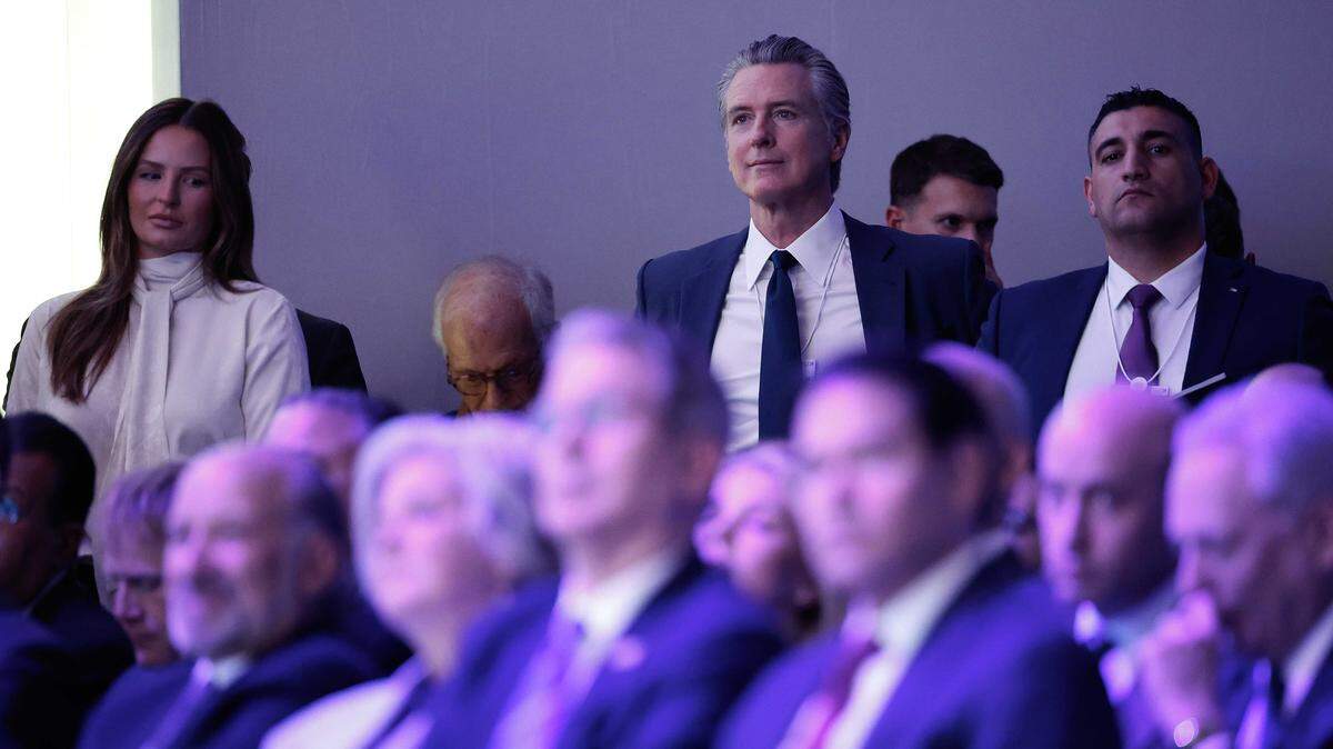 California Gov. Gavin Newsom, center, listens from the sidelines of the World Economic Forum as President Donald Trump speaks Wednesday in Davos, Switzerland. Newsom’s planned remarks at a U.S. pavilion event were canceled after pressure from Trump administration officials, according to the Governor’s Office.