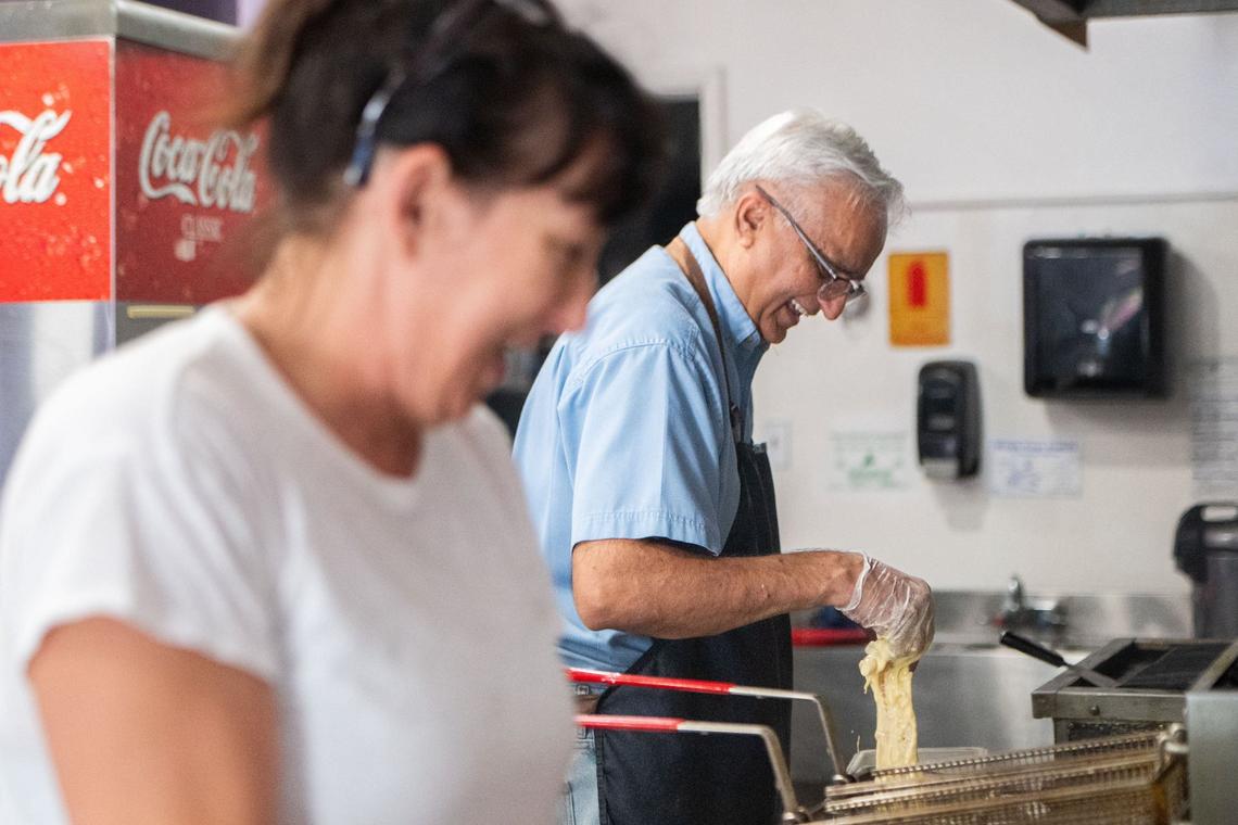 Kara Nelson, left, laughs along with Pawitar Jeet Sandhu, owner of PJ’s Diner Fish and Chips, while he batters fish on Wednesday at his restaurant, located in East Sacramento’s Italian Corners. Sandhu opened up his restaurant to bring “a bit of English culture” to East Sacramento, and he said he hopes “to be one of the most recognizable fish and chip shops maybe in Sacramento one day.”
