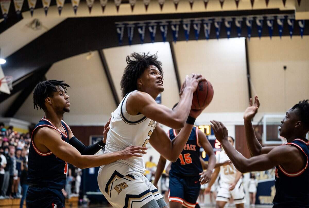Elk Grove center/forward DaJon Lott Jr. (21) goes up to score as Cosumnes Oaks Brandon Hayward (1), left, and Ja’len Flenory defend during the first half of the high school boys basketball game Feb. 4, at Elk Grove High School. The Thundering Herd beat the Wolfpack 81-58 on senior night at home in Elk Grove.