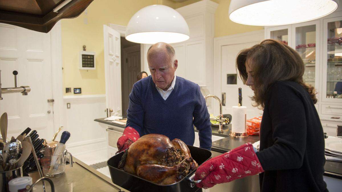 Then-Gov. Jerry Brown and First Lady Anne Gust Brown pull a turkey out of the oven while hosting a dinner in the Governor’s Mansion for family and friends in December 2015.