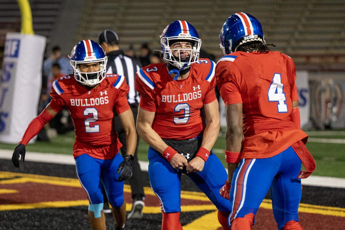 Ryder Lyons (3) of the Folsom Bulldogs celebrates with teammates Jameson Powell (2) and Isaiah Williams (4) after Williams' touchdown catch in the first half of the CIF Sac-Joaquin Section football Division I championship game against the Oak Ridge Trojans on Friday, Nov. 28, 2025, at Hughes Stadium in Sacramento.