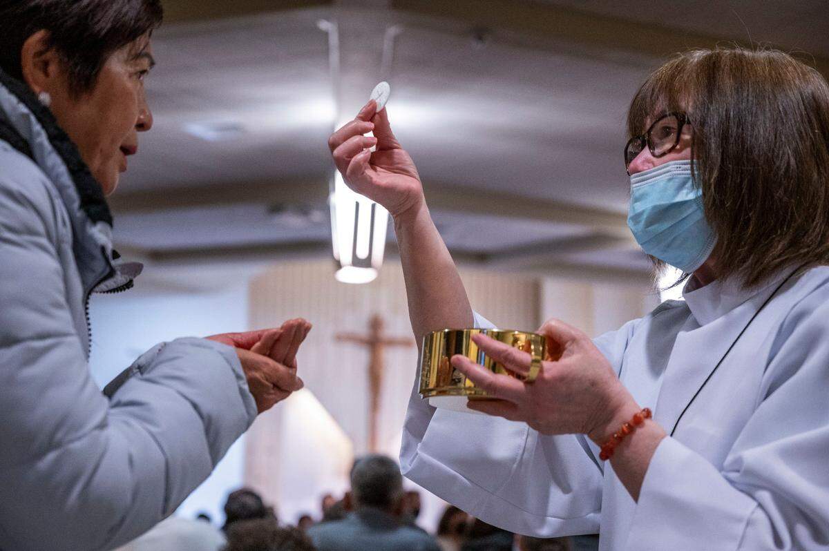 Nguyet Dang, a eucharist minister, gives the holy communion as members of the Vietnamese Martyrs Parish in South Sacramento celebrate Holy Thursday with a mass and eucharistic adoration.