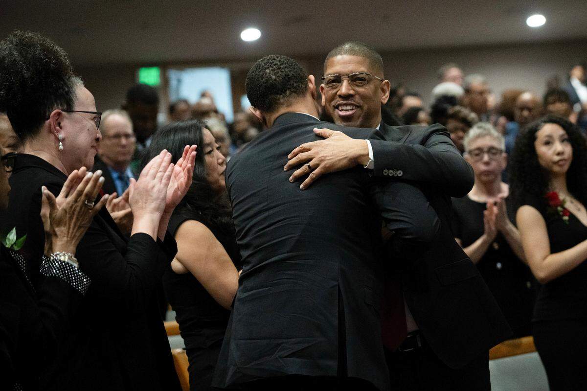 Former Sacramento mayor Kevin Johnson hugs Ronald West after West spoke about their mother Georgia West, the driving force behind Underground Books in Oak Park, at her celebration of life memorial service at Saint Paul Church in Sacramento on Thursday.