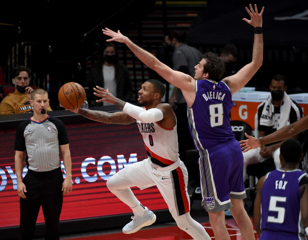Portland Trail Blazers guard Damian Lillard, left, dives to the basket as Sacramento Kings forward Nemanja Bjelica defends during the first half of an NBA basketball game in Portland, Ore., Thursday, March 4, 2021. (AP Photo/Steve Dykes)