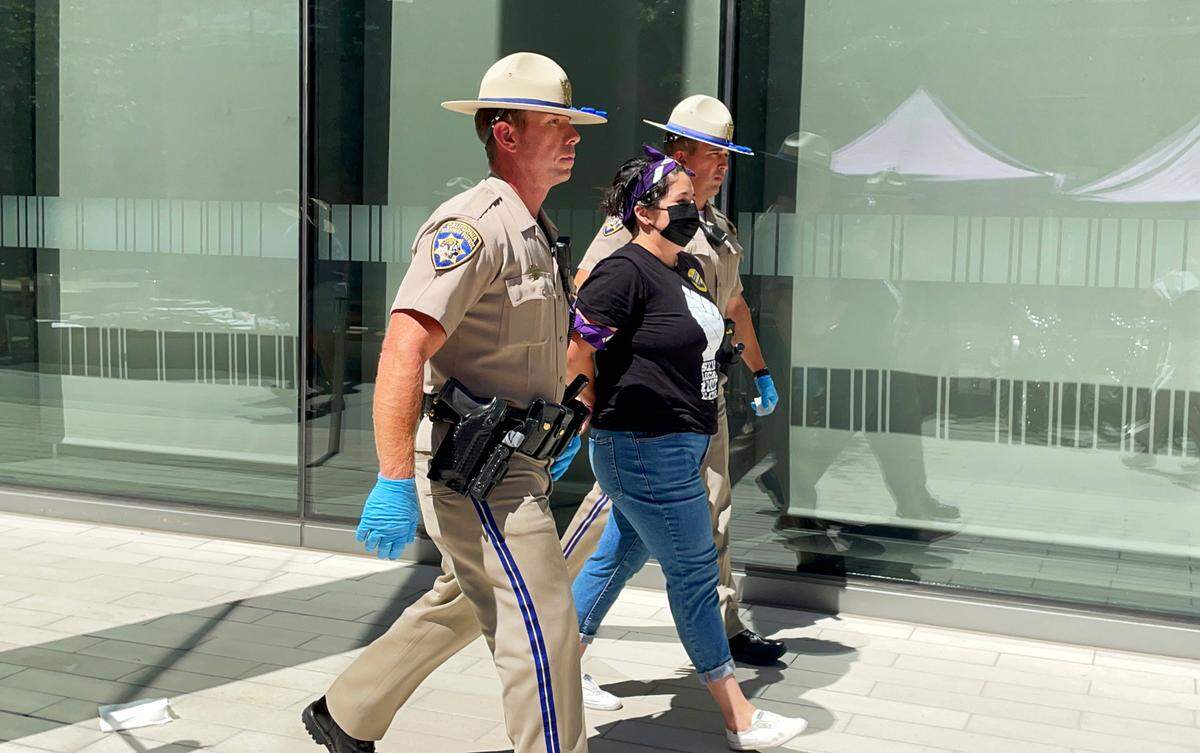 Sacramento City Councilwoman Katie Valenzuela is detained by CHP officers on Wednesday at an SEIU Local 1000 protest at the Capitol swing space offices on O Street in downtown Sacramento.