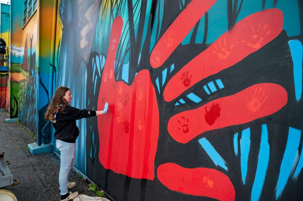 Jurni Montiel, 14, one of the Native youth artists, adds her handprint to a red hand on a Miwok Middle School mural during an unveiling ceremony on Saturday celebrating the school’s historic name change from Sutter Middle School. The red hand print is meant to raise awareness of the national crisis of missing and murdered Indigenous women.