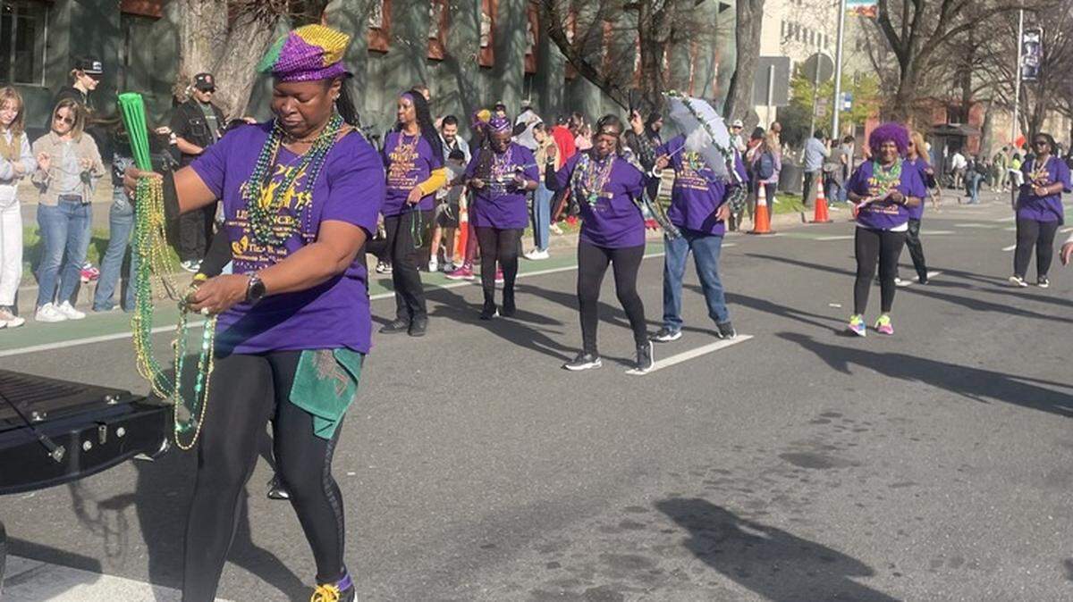 Participants in the Mardi Gras Festival and City of Trees Parade hand out beads to attendees on Saturday.