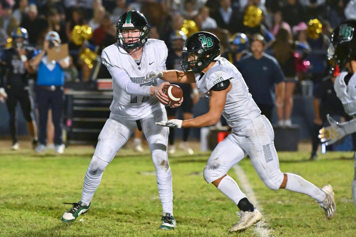 Twelve Bridges Raging Rhinos quarterback Whit Kruse (17) hands off to running back Nathan Crawford (14) for a 6-yard gain in the first half against the Sutter Huskies on Thursday at Sutter Union High School.